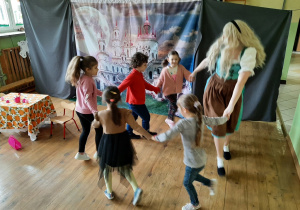 Na scenie - dzieci zaproszone przez aktorkę tańczą z nią w kole - kolejne ujęcie. W tle dekoracja.