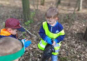 Dzieci z workami sprzątają przydrożny teren lasu