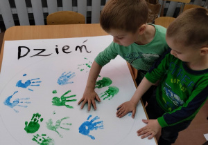 Dzieci z grupy 3-4 latków robią odcisk dłoni na grupowym plakacie