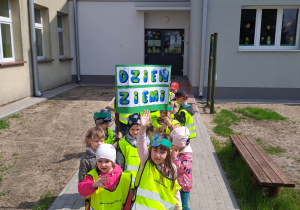 Dzieci przed budynkiem przedszkola z transparentem na Dzień Ziemi