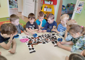 Dzieci z grupy 5,6 latków ozdabiają farbą szablin krowy.