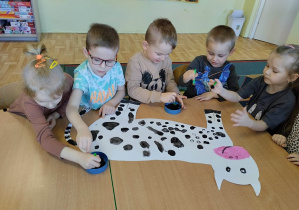 Dzieci z grupy 3,4,5 latków ozdabiają farbą szablin krowy.