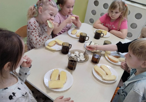 Grupa dzieci przy stoliku podczas degustacji różnych serów.