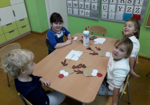 Dzieci wykonują mikołaja z papieru.