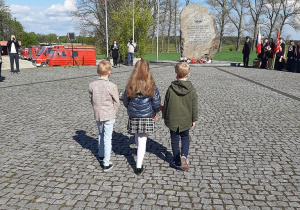 Delegacja dzieci idzie złożyć wiązankę pod obelisk.
