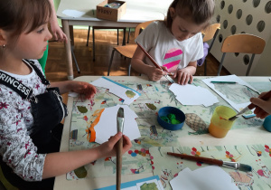 Dziewczynki przy stoliku malują farbami kontur mapy Polski.