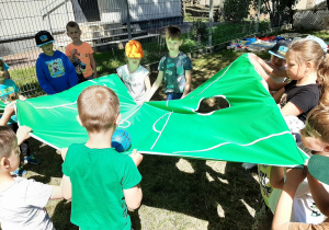 Grupa dzieci uczestniczy w zabawie z piłką.