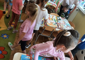Dzieci przy stolikach oglądają wybrane książki w ramach akcji "Jak nie czytam jak czytam"