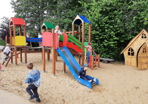 Dzieci na placu zabaw na kolorowej zjeżdżalni.