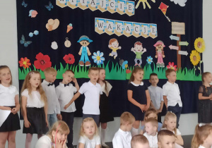 Dzieci z grupy 5, 6 latków podczas występu na tle kolorowej dekoracji.