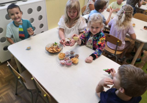 Dzieci siedzące przy stoliku podczas słodkiego poczęstunku.