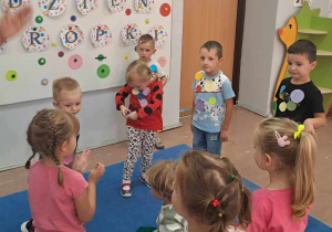 Dzieci w czasie zabawy na dywanie z papierowymi kropkami