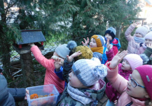 Dzieci nasypujące ziarenka do karmnika