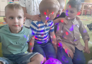 Chłopcy siedzą przed kolorową świecącą kulą