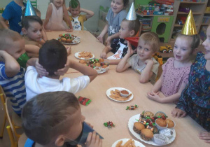 Przedszkolaki siedzą przy stole podczas poczęstunku