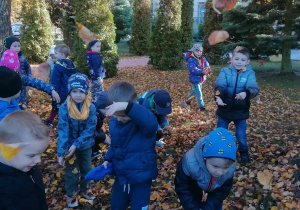 Dzieci w ogrodzie podczas zabawy jesiennymi listkami