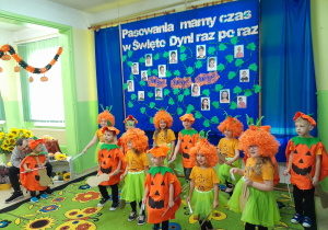 Dzieci w dyniowych kostiumach prezentują piosenkę.