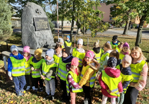 Grupa przedszkolaków pozująca do fotografii przy obelisku w Wartkowicach upamiętniającym poległych w walce o ojczyznę