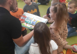 Tata dziecka czyta przedszkolakom książkę