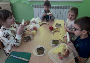 Dzieci przy stolikach wykonują "misiowe kanapki".