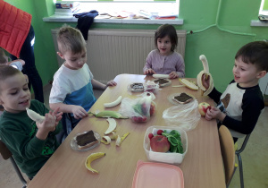 Dzieci przy stolikach wykonują "misiowe kanapki".