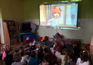 Dzieci oglądają bajkę o przygodach Misia Uszatka.