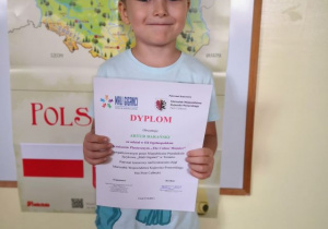 Chłopiec prezentuje dyplom za udział w konkursie.
