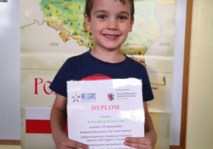 Chłopiec prezentuje dyplom za udział w konkursie.