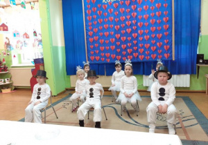 Dzieci przebrane za bałwanki i śnieżynki prezentują taniec na krzesełkach.