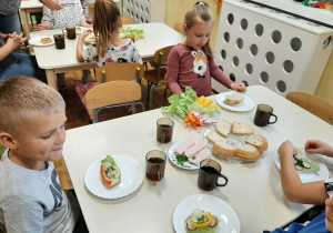 Grupa 5,6 latków. Dzieci siedzą przy stoliku, przygotowują zdrowe kanapki ze zdrowych produktów
