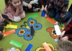 Dzieci siedzą w kole i wybierają kolor kartki do wróżby