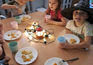 Dzieci jedzą posiłek wśród lampionów