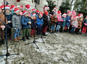 Dzieci stoją przed mikrofonami i śpiewają pastorałkę