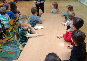 Dzieci słuchają opowieści czytanej przez pracownika biblioteki