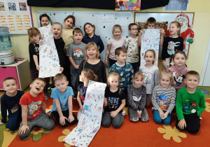 Dzieci pozują do fotografii, trzymają wykonane przez siebie obrazkowe listy do Mikołaja.