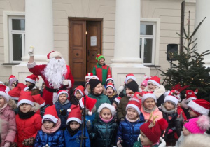 Przedszkolaki pozują do zdjęcia z Mikołajem i elfem.