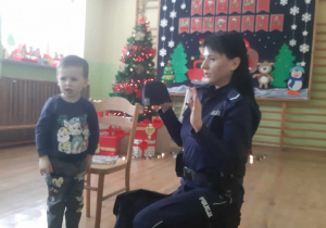 Policjantka pokazuje dzieciom czapkę policyjną