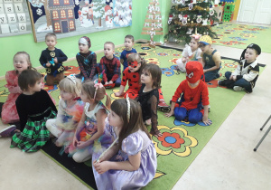 Dzieci przebrane w kostiumy balowe oglądają karnawałową bajkę.