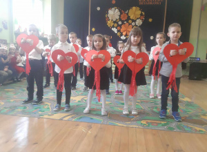 Dzieci z grupy starszaków podczas śpiewu z czerwonymi sercami