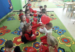 Dzieci na dywanie bawią się w grę "Złap balonik".