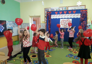 Zabawy taneczne dzieci z balonami na tle walentynkowej dekoracji.