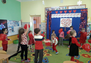 Zabawy taneczne dzieci z balonami na tle walentynkowej dekoracji.