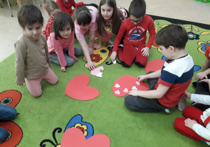Dzieci na dywanie grają w "serduszkowe kółko i krzyżyk".