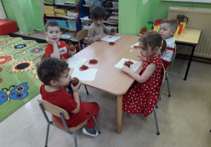Dzieci przy stolikach zajadają się walentynkowymi muffinkami.