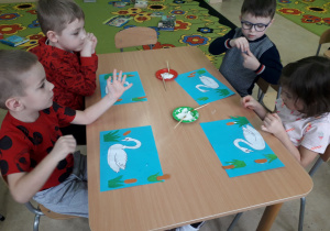 Dzieci przy stolikach wykonują pracę plastyczną "Brzydkie kaczątko".