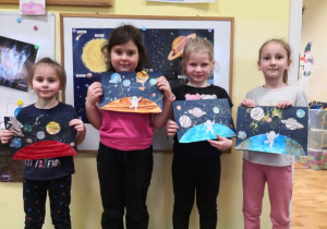 Dziewczynki prezentują wykonaną pracę plastyczną przedstawiającą Układ Słoneczny.