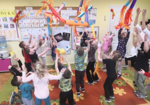 Przedszkolaki podczas zabawy tanecznej z kolorowymi rakietami.