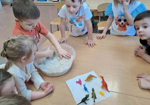 Dzieci w czasie zabawy z piaskiem szukają dinozaurów