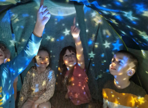 Dzieci oglądają gwiazdy w namiocie wyświetlane za pomocą projektora