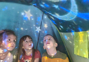 Dzieci oglądają gwiazdy w namiocie wyświetlane za pomocą projektora
